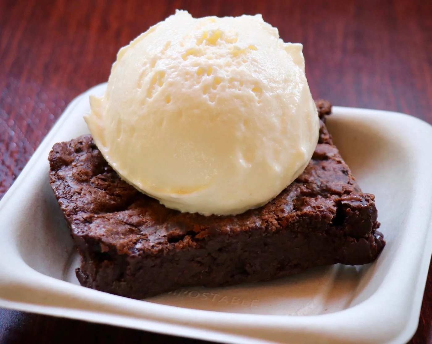 A warm brownie topped with a scoop of vanilla ice cream
