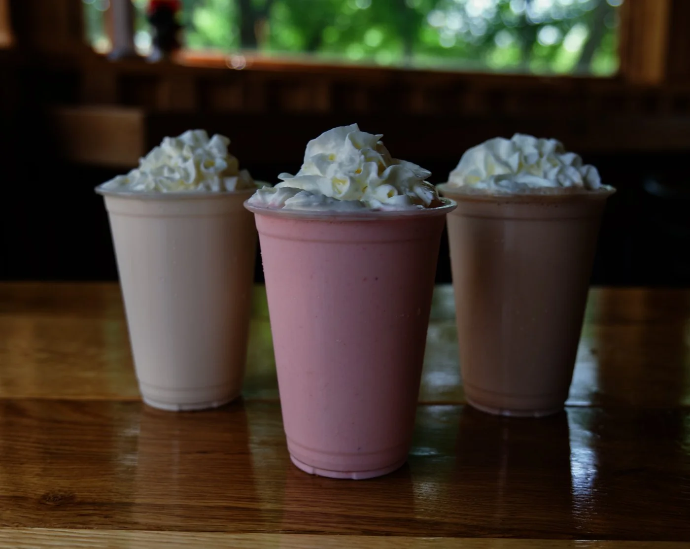 Three handspun milkshakes topped with whipped cream on the dining room table