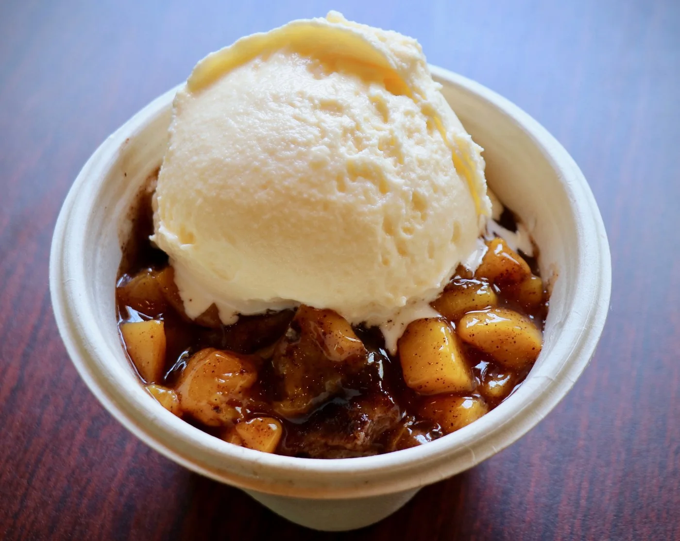 Peach cobbler under a scoop of vanilla ice cream