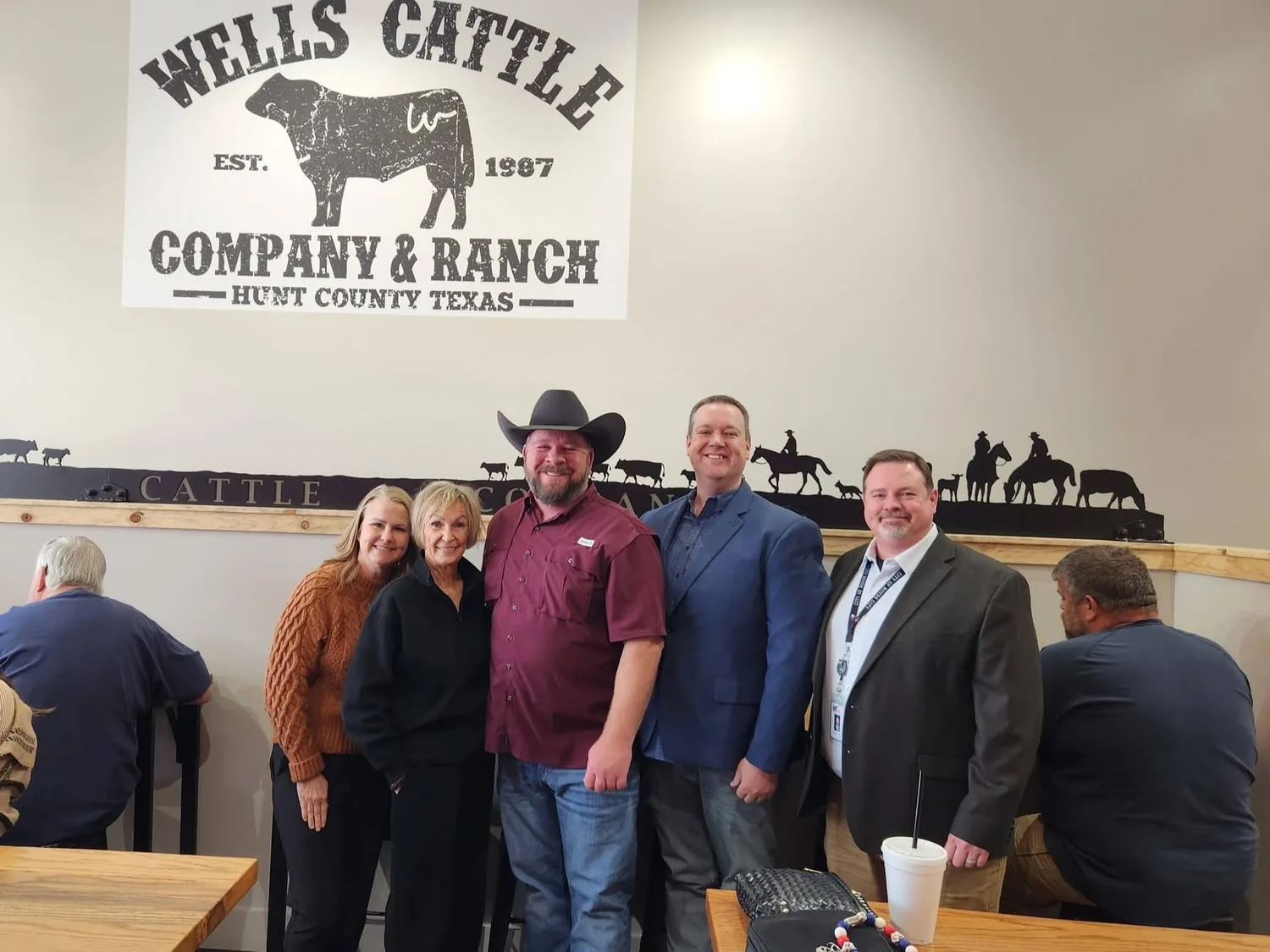 Lee Wells with family and city officials under the Wells Cattle Company & Ranch wall mural