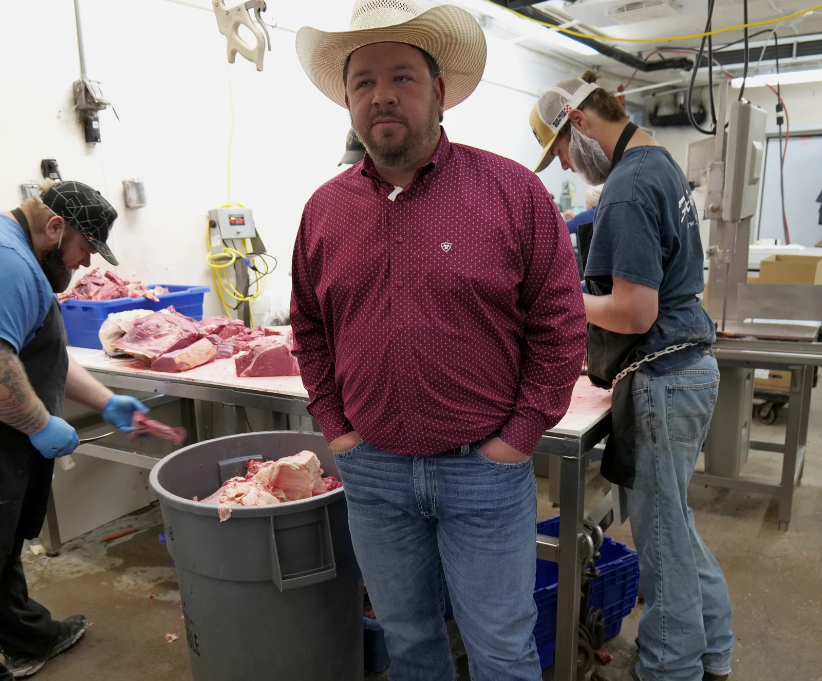 A Wells Cattle Co. representative standing on the processing floor while butchers break down beef carcasses