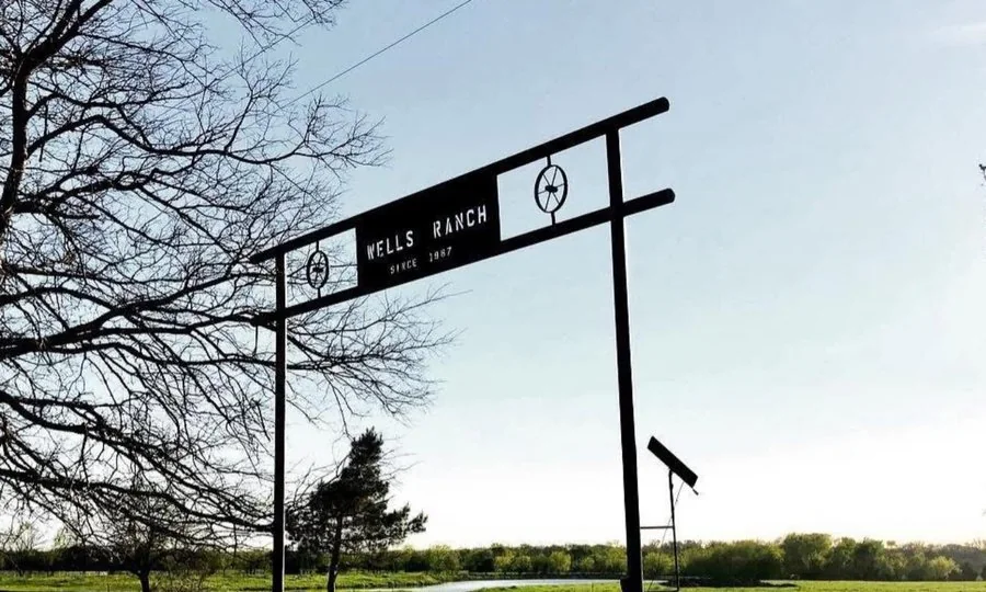 The Wells Ranch entrance gate, a steel sign over the pasture drive